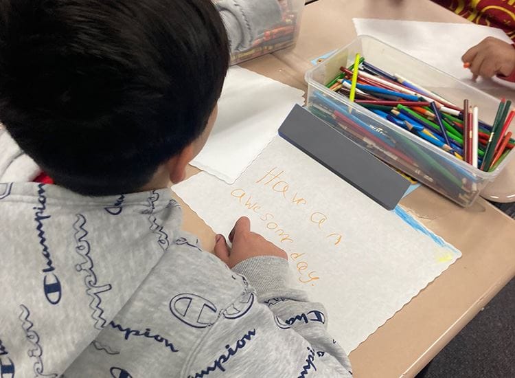 Student at Cowlishaw Elementary School writing a positive message on a paper during class.
