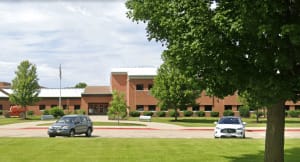 Exterior view of Owen Elementary School in Naperville, showing the brick building, green lawn, and flagpole.