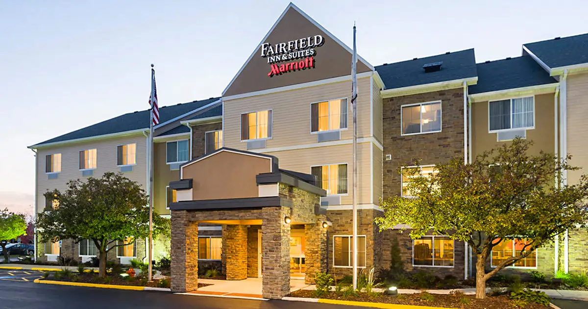 Places to Stay 18 Fairfield Inn and Suites West Naperville hotel exterior with illuminated entrance and landscaped front drive.