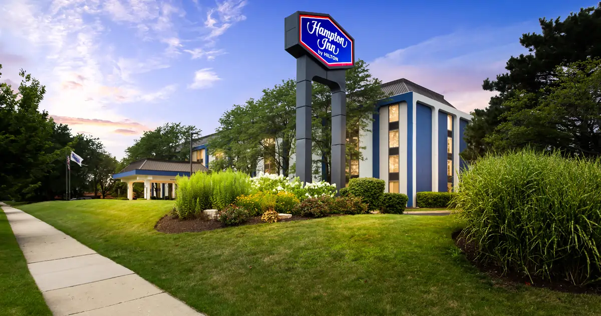 Places to Stay 17 Hampton Inn by Hilton Chicago-Naperville hotel exterior with landscaped grounds and roadside sign in Naperville, Illinois.