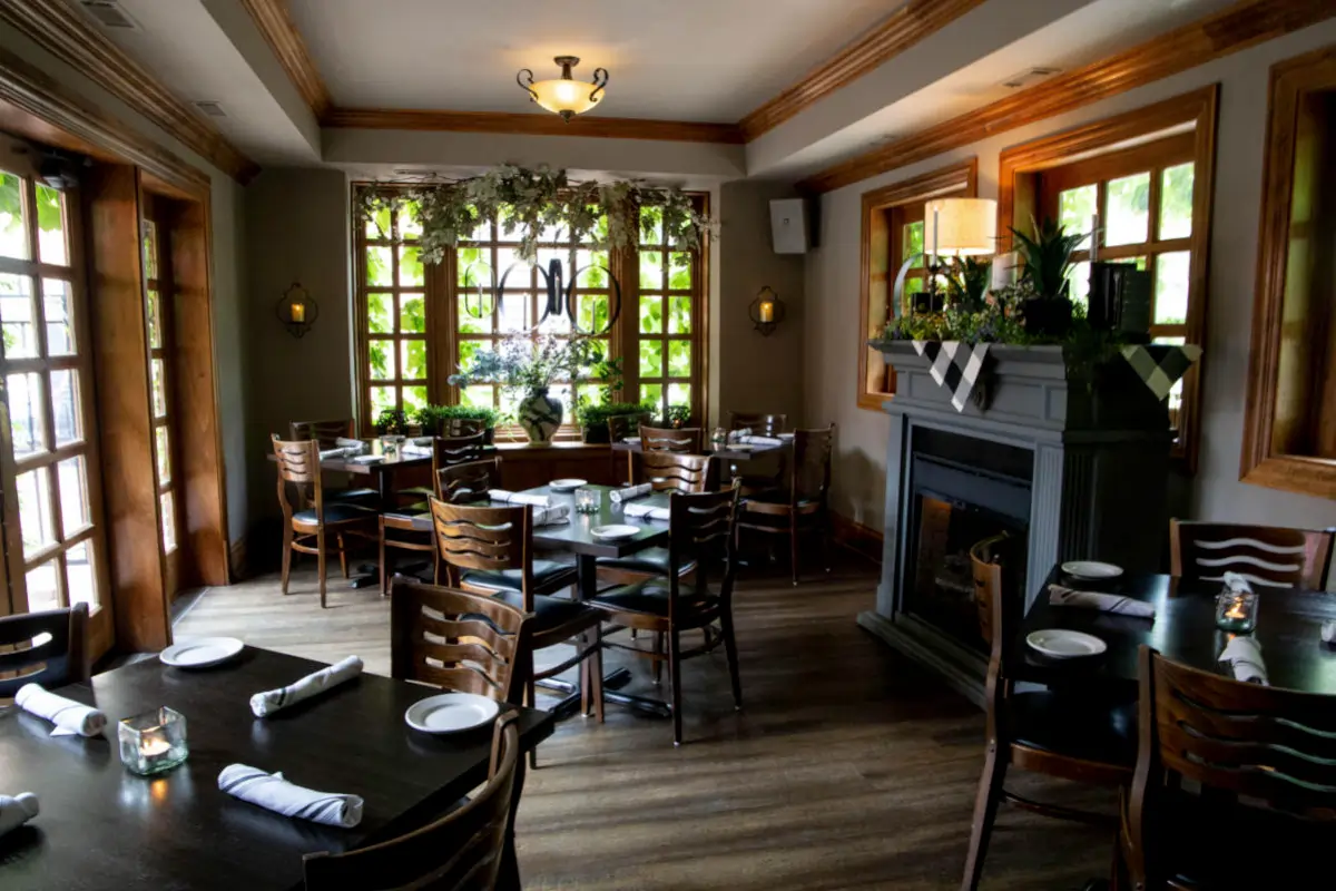 Dining room interior at Ivy Restaurant in Wheaton, Illinois, featuring wood tables, fireplace seating, and an upscale local restaurant atmosphere for steaks, chops, and seafood