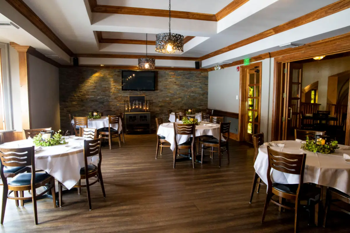 Private dining room at Ivy Restaurant in Wheaton, Illinois, featuring round tables, fireplace wall, and an upscale space for local dining and special events