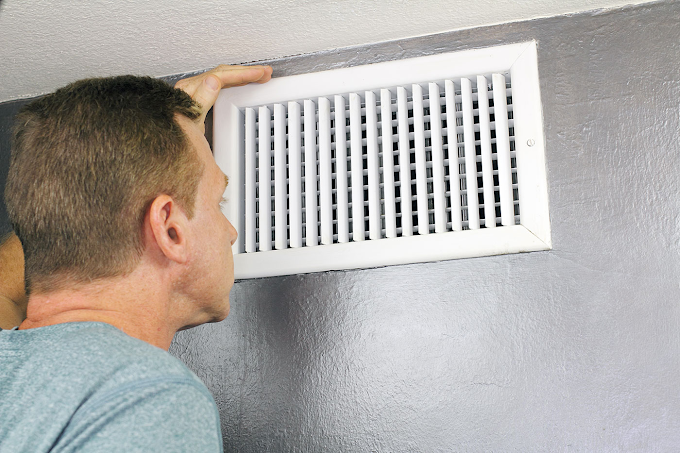 Indoor environmental inspector checking an HVAC vent for air quality and moisture concerns in a Naperville home.