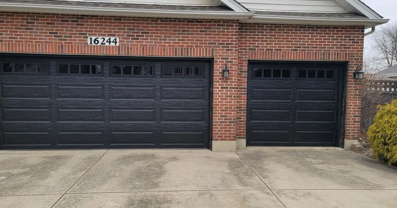 Black residential garage doors installed on a brick home by All Style Door in the Naperville area.