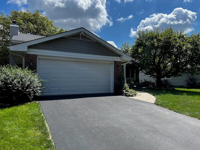 White residential garage door installed by All Style Door on a Naperville area home with asphalt driveway and front lawn.