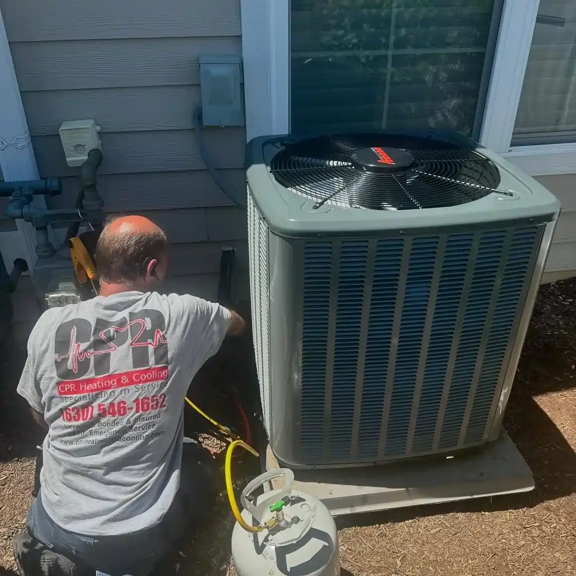 CPR Heating & Cooling Inc technician servicing an outdoor air conditioning unit at a Naperville area home.