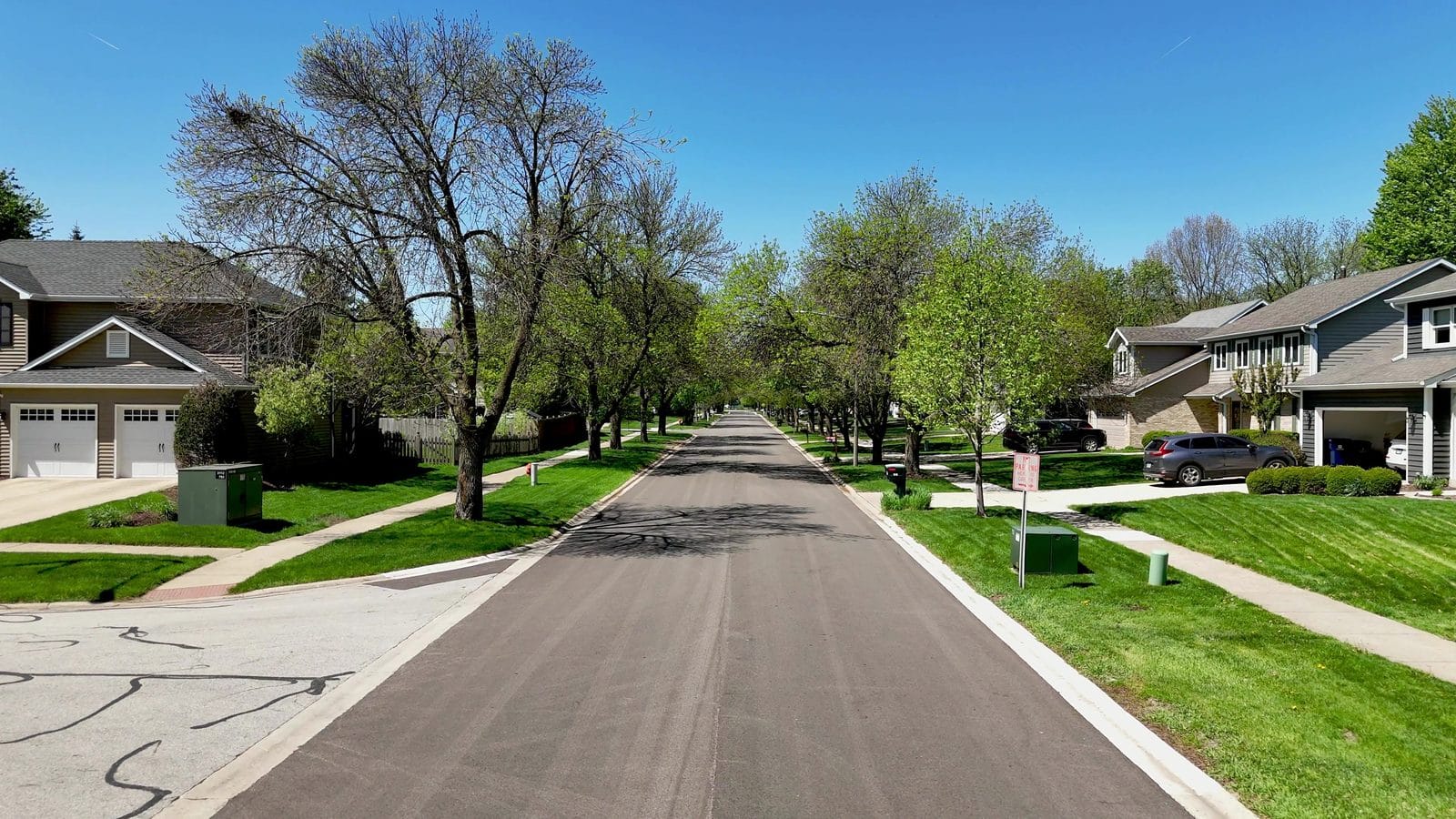 First-year rent vs buy costs in Naperville: tree-lined street with two-story homes and garages