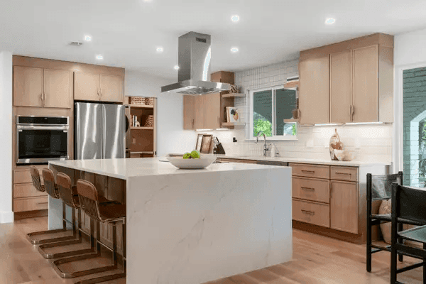 Modern kitchen with large island, light wood cabinets, stainless steel appliances, and smooth countertop surfaces for a Naperville area home improvement project.