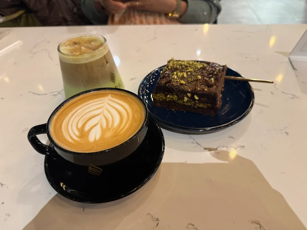 Haraz Coffee House latte with latte art and Dubai Brownie with pistachios on dark plate near Naperville 2026