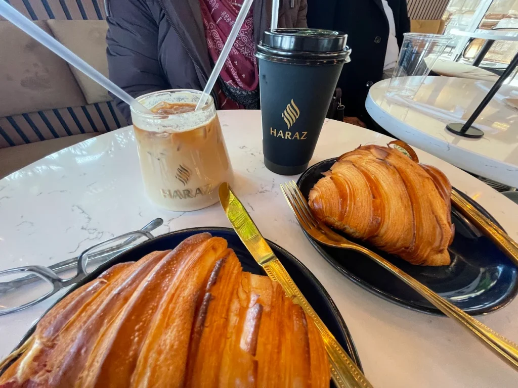Haraz Coffee House flaky layered pastry on dark plate with gold cutlery and iced latte near Naperville 2026