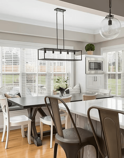 Bright dining area with custom built-in bench seating, white cabinetry, large windows, pendant lighting, and kitchen island for a Naperville area home.
