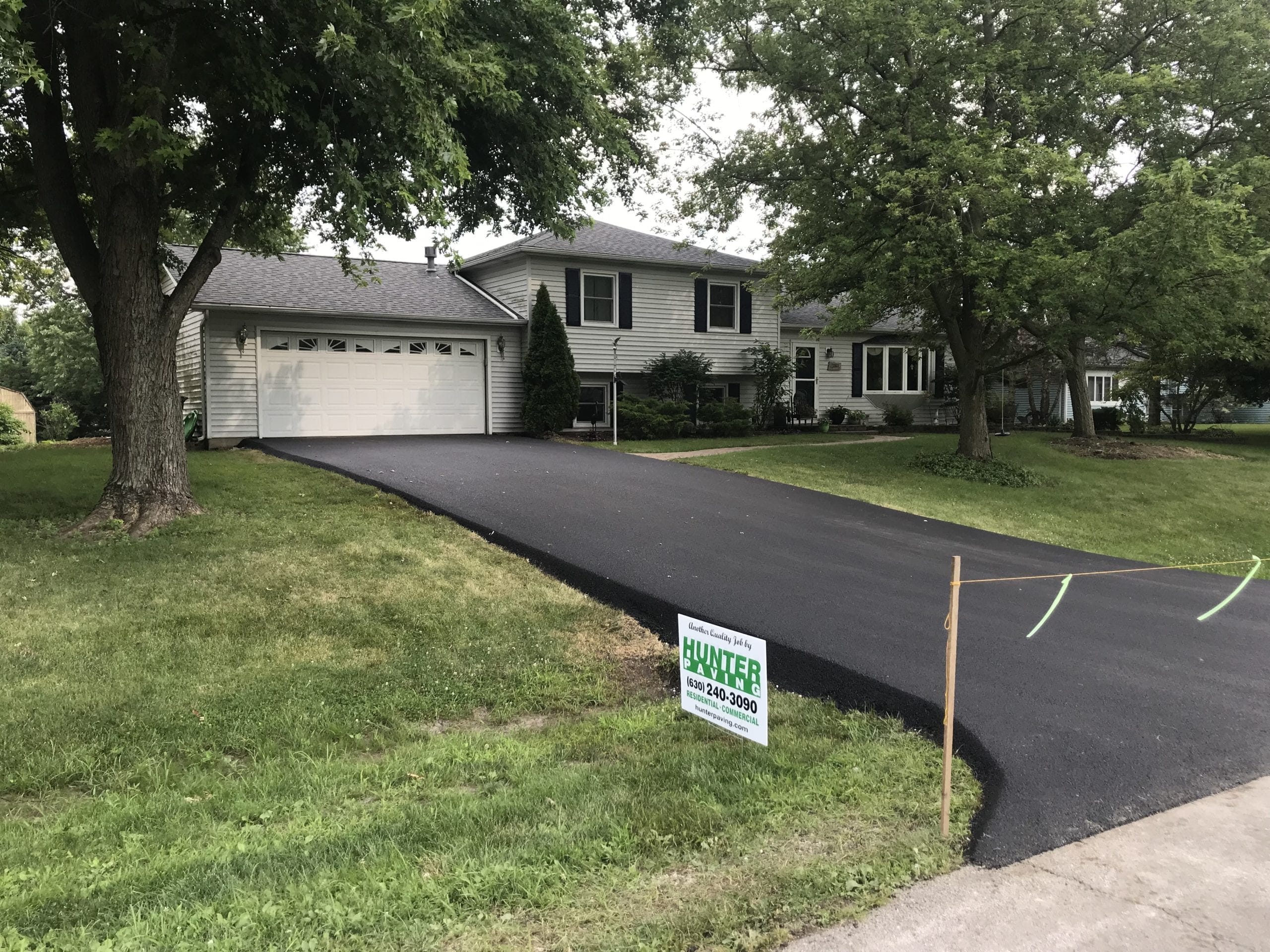 Freshly paved asphalt driveway in front of a residential home for Hunter Paving and Excavating services in the Naperville area.