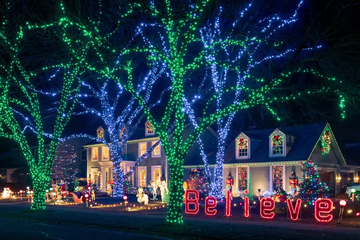 Lightville Christmas lights display in Naperville with decorated homes, glowing trees, holiday figures, and Believe sign.