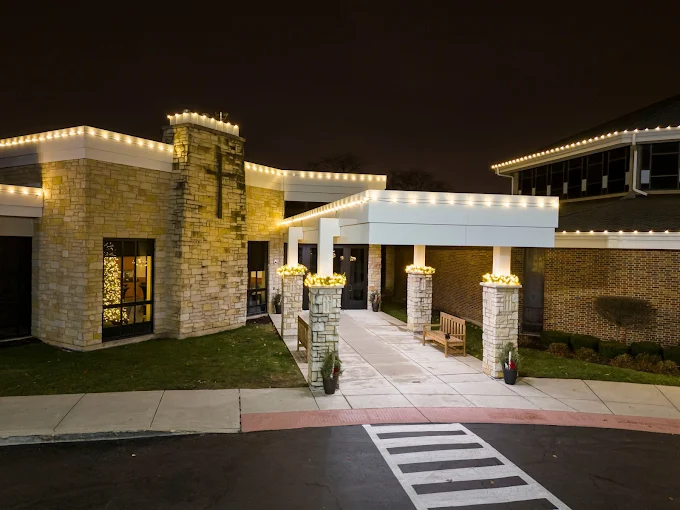 Lightville holiday display in Naperville with warm white Christmas lights outlining a stone building entrance and roofline.