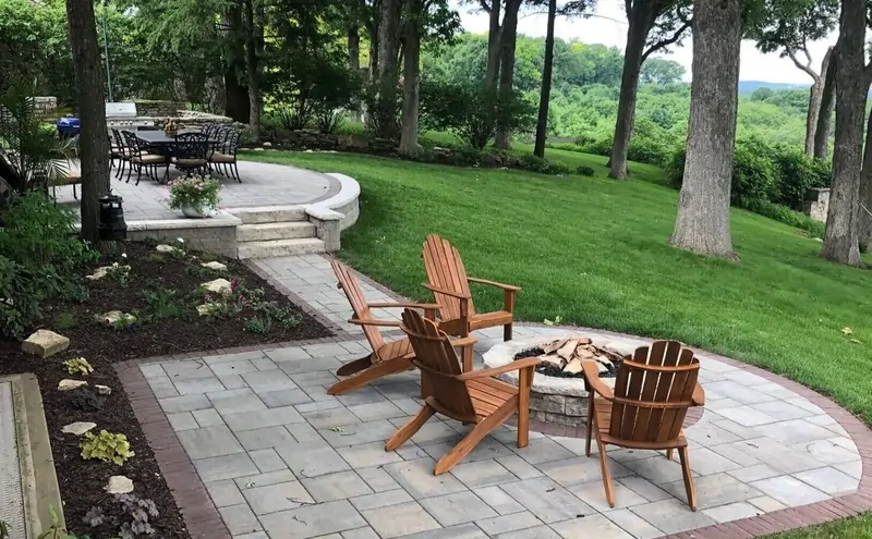 Backyard paver patio with fire pit, seating, lawn, and landscaped garden beds by Martins Express Landscaping in Naperville.