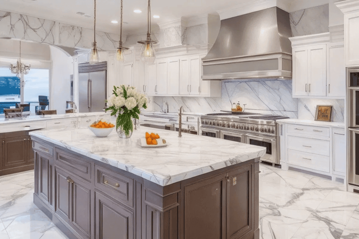 Luxury kitchen remodel with marble countertops, white cabinetry, large island, pendant lighting, stainless steel range, and stone backsplash in a Naperville area home.