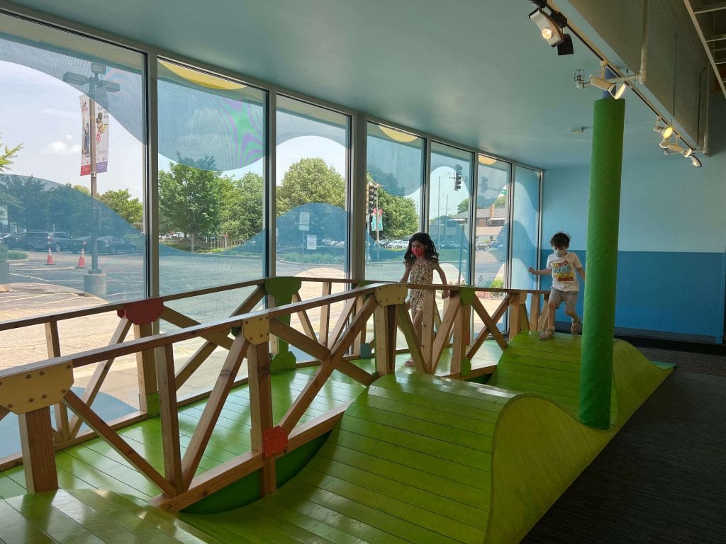 Children play on an indoor bridge style exhibit at a childrens museum in Naperville, Illinois, highlighting family activities, hands on learning, and things to do in Naperville