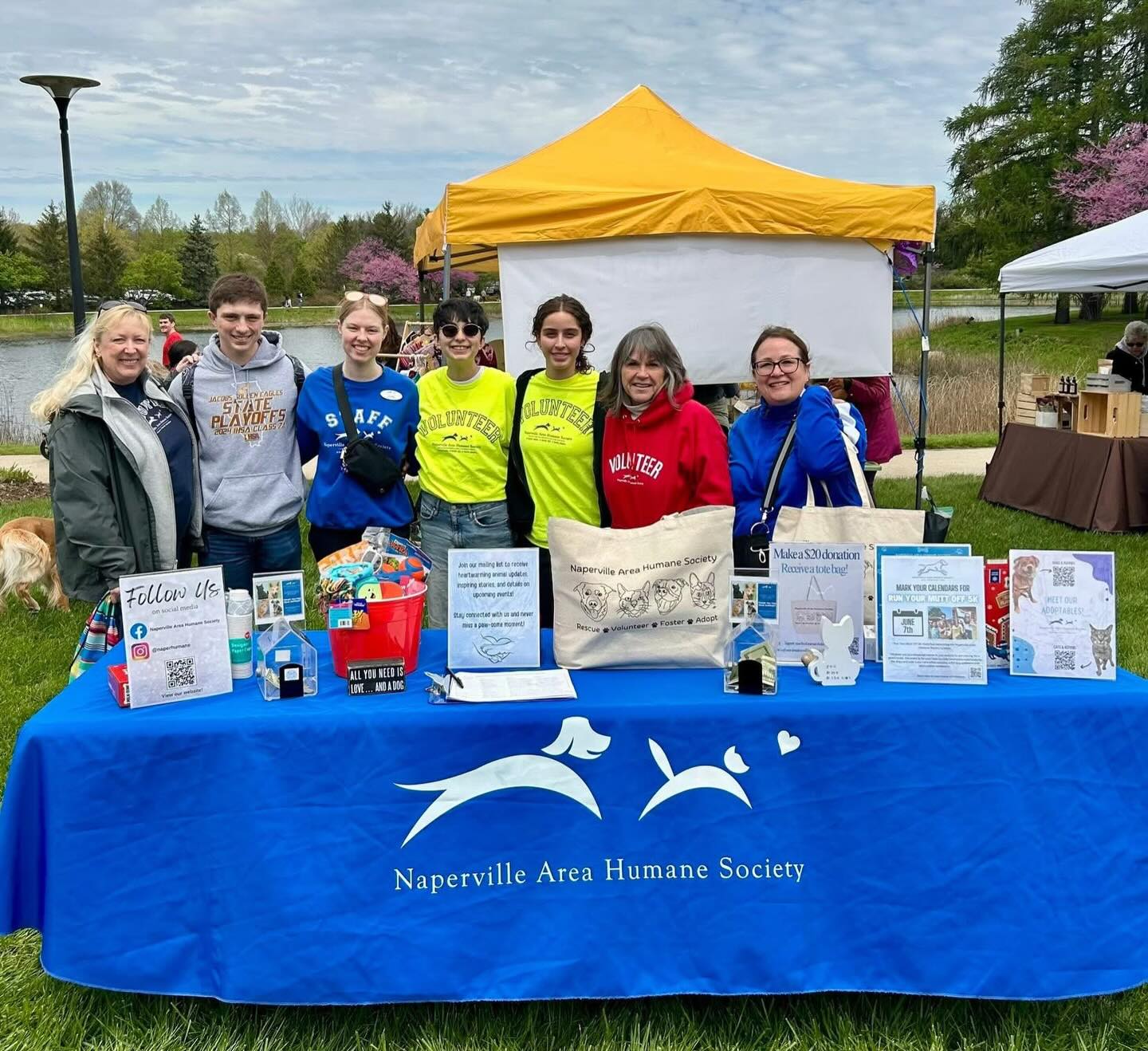 Naperville Area Humane Society staff and volunteers at an outdoor community event booth in Naperville, Illinois, promoting local nonprofit outreach, pet adoption, and volunteer engagement