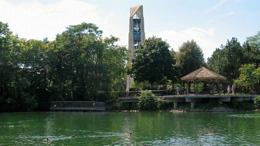Millennium Carillon in Naperville IL viewed across the DuPage River with a riverside pavilion and trees