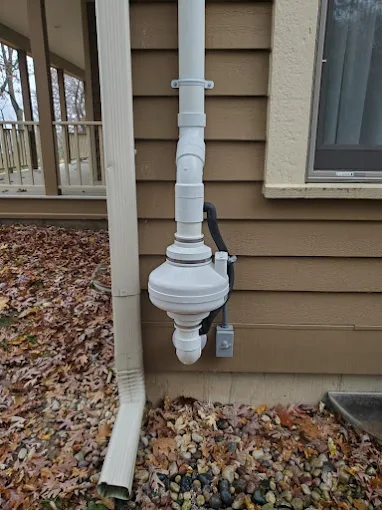 Exterior radon mitigation fan and vent pipe installed on a residential home by Pro Radon Mitigations.