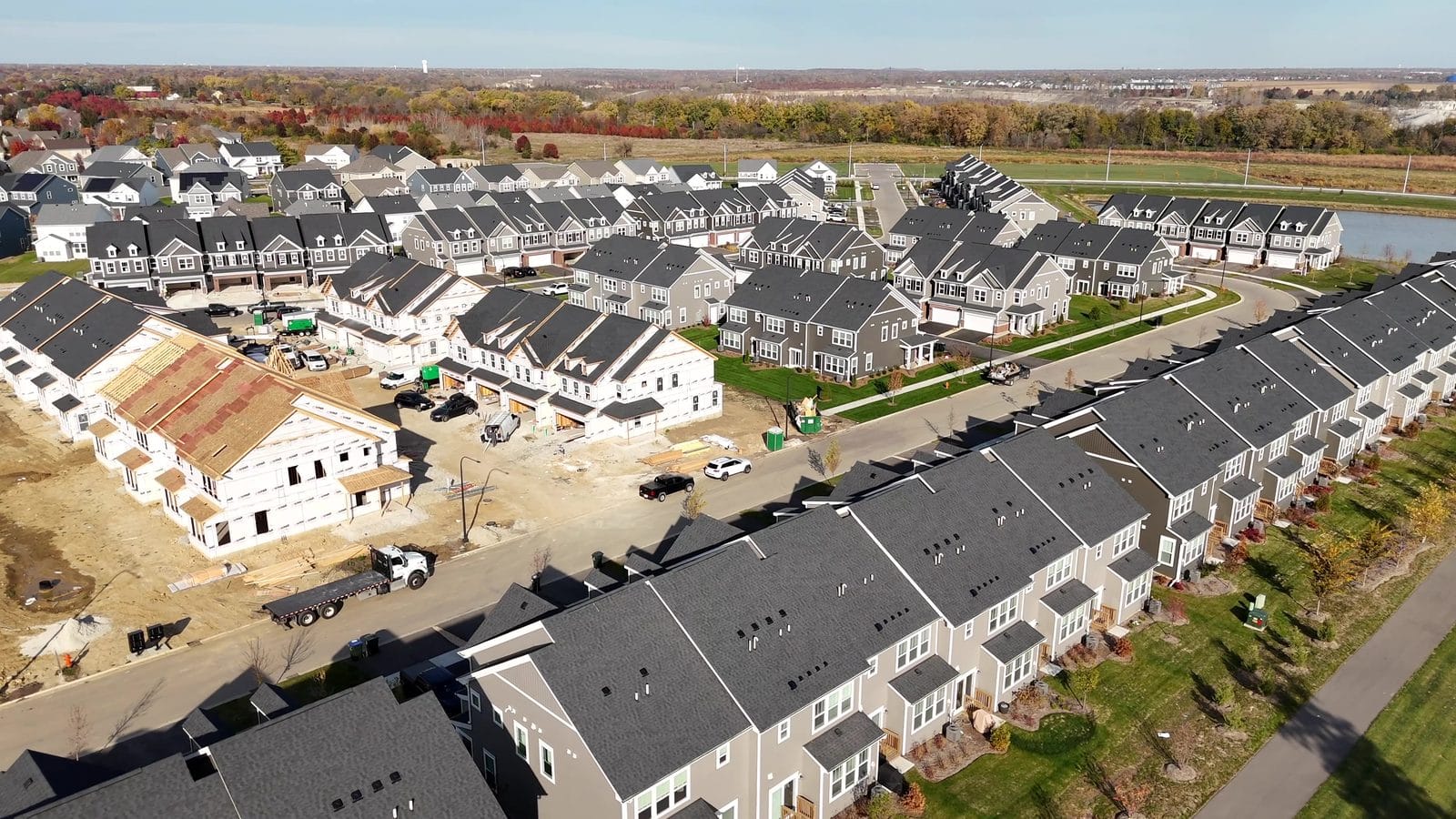 Radon testing new construction: house-wrapped Naperville townhomes beside finished rows, from above
