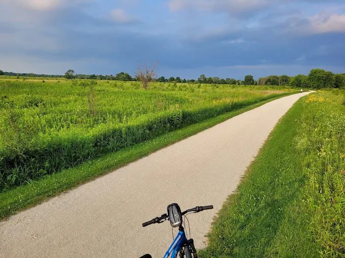 Bike trail at Springbrook Prairie in Naperville, Illinois with open prairie fields and wide paved path.