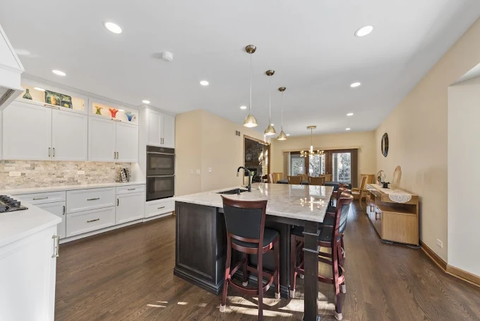 Kitchen island countertop project by TC Stone Enterprise with white stone surfaces, custom cabinets, and pendant lighting in Naperville.