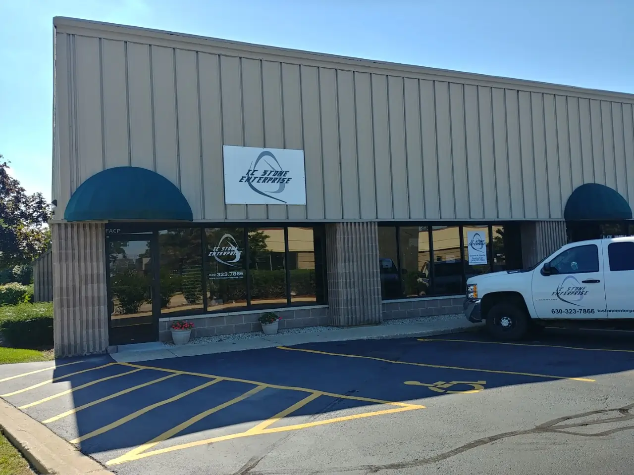 TC Stone Enterprise storefront in Naperville, Illinois with branded sign, front windows, parking area, and service vehicle.