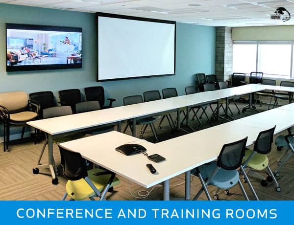 Conference and training room with wall-mounted TV, projection screen, tables, chairs, and audiovisual setup for The TV Pro services in the Naperville area.