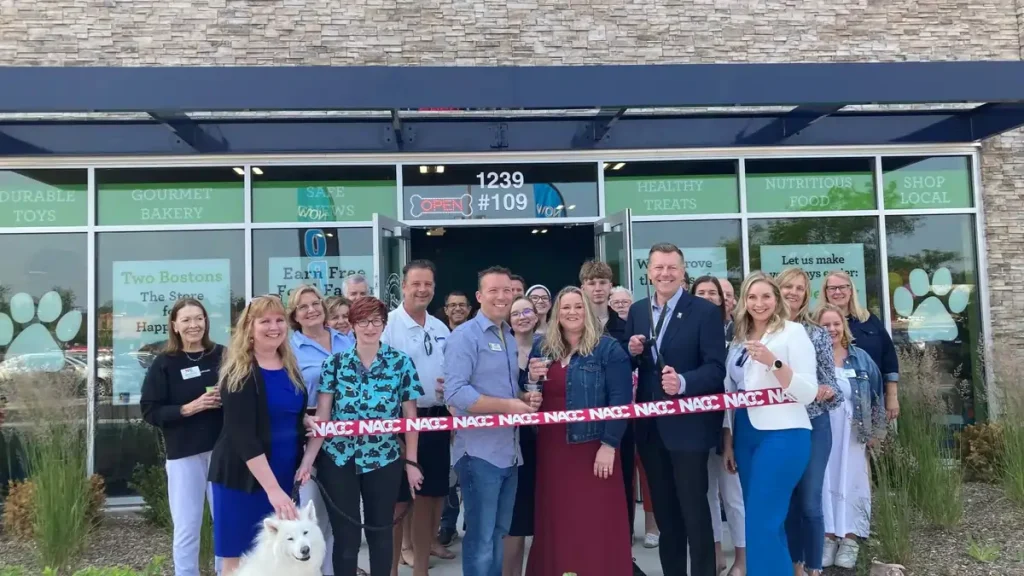 Two Bostons team members at a Naperville ribbon cutting event outside the pet store with local business supporters.