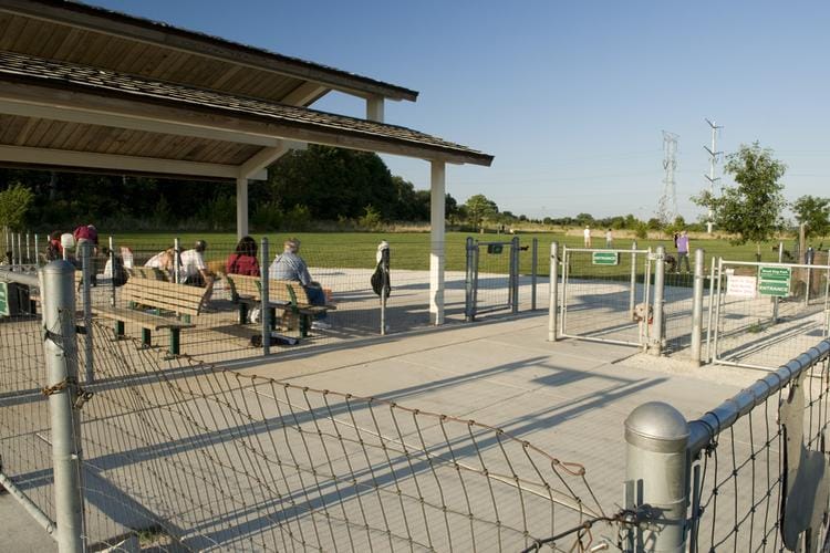 Whalon Lake dog park entrance in Naperville, Illinois with fenced play areas, seating, and open recreation space.
