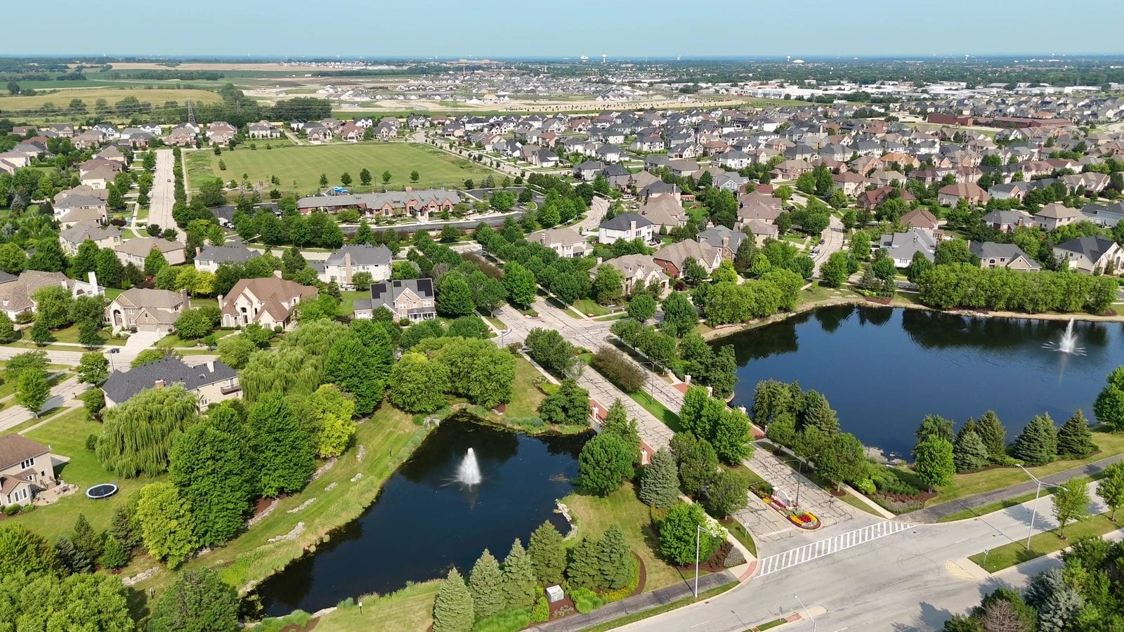 Aerial of Naperville home lots and rooftops beside fountain ponds, for finding your tax district
