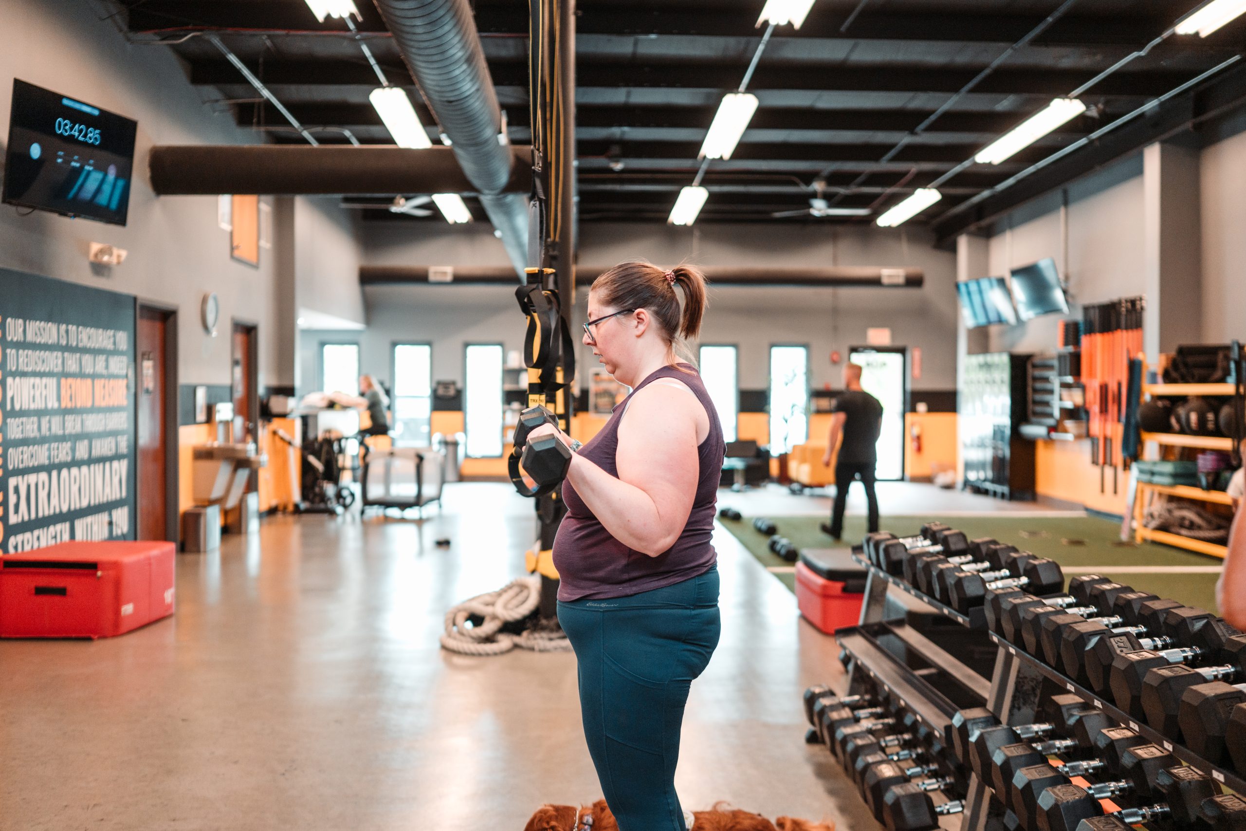 Client performing a dumbbell strength exercise inside Beyond Measure Fitness Training in Naperville, Illinois.