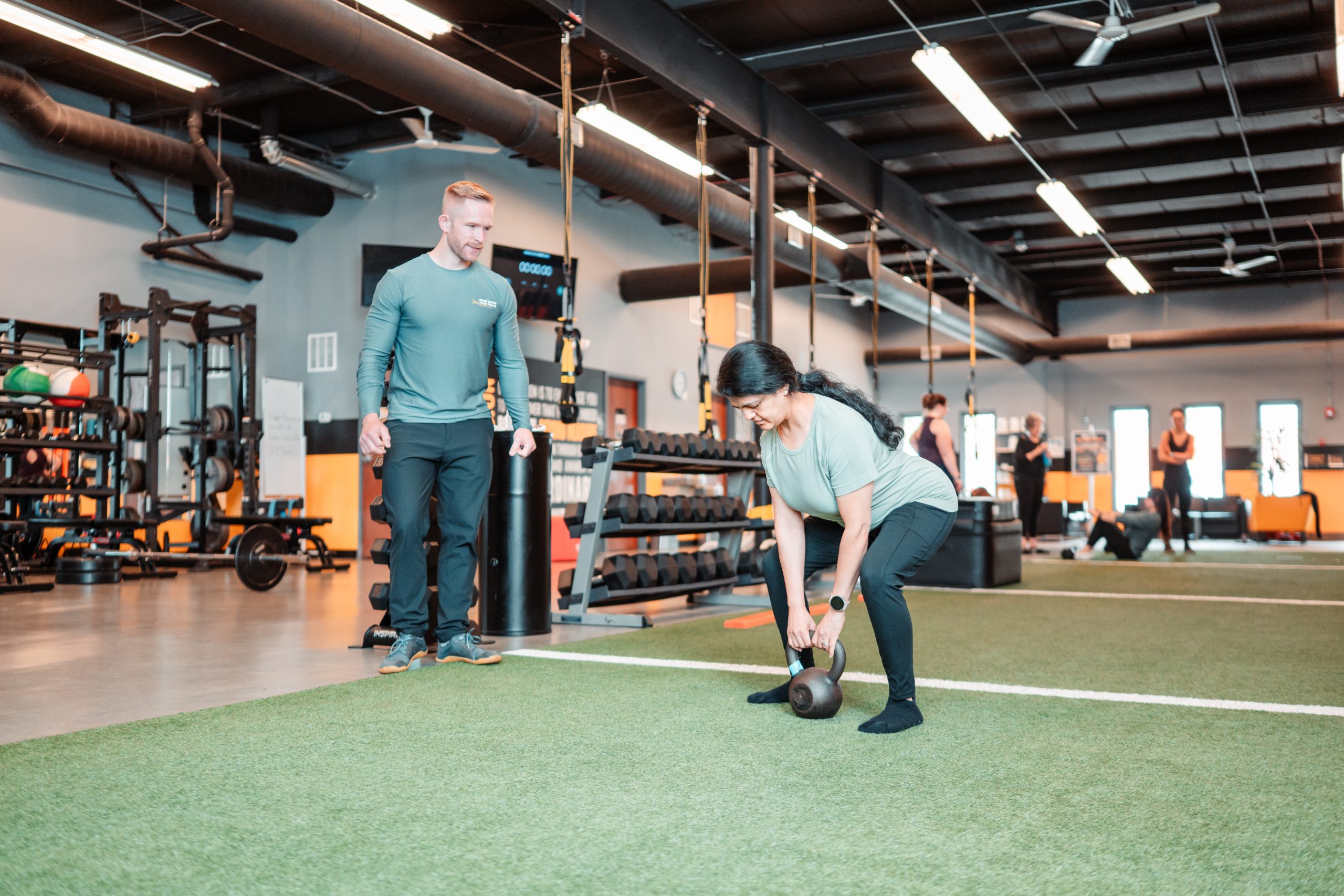 Personal trainer coaching a client performing a kettlebell exercise at Beyond Measure Fitness Training in Naperville, Illinois.