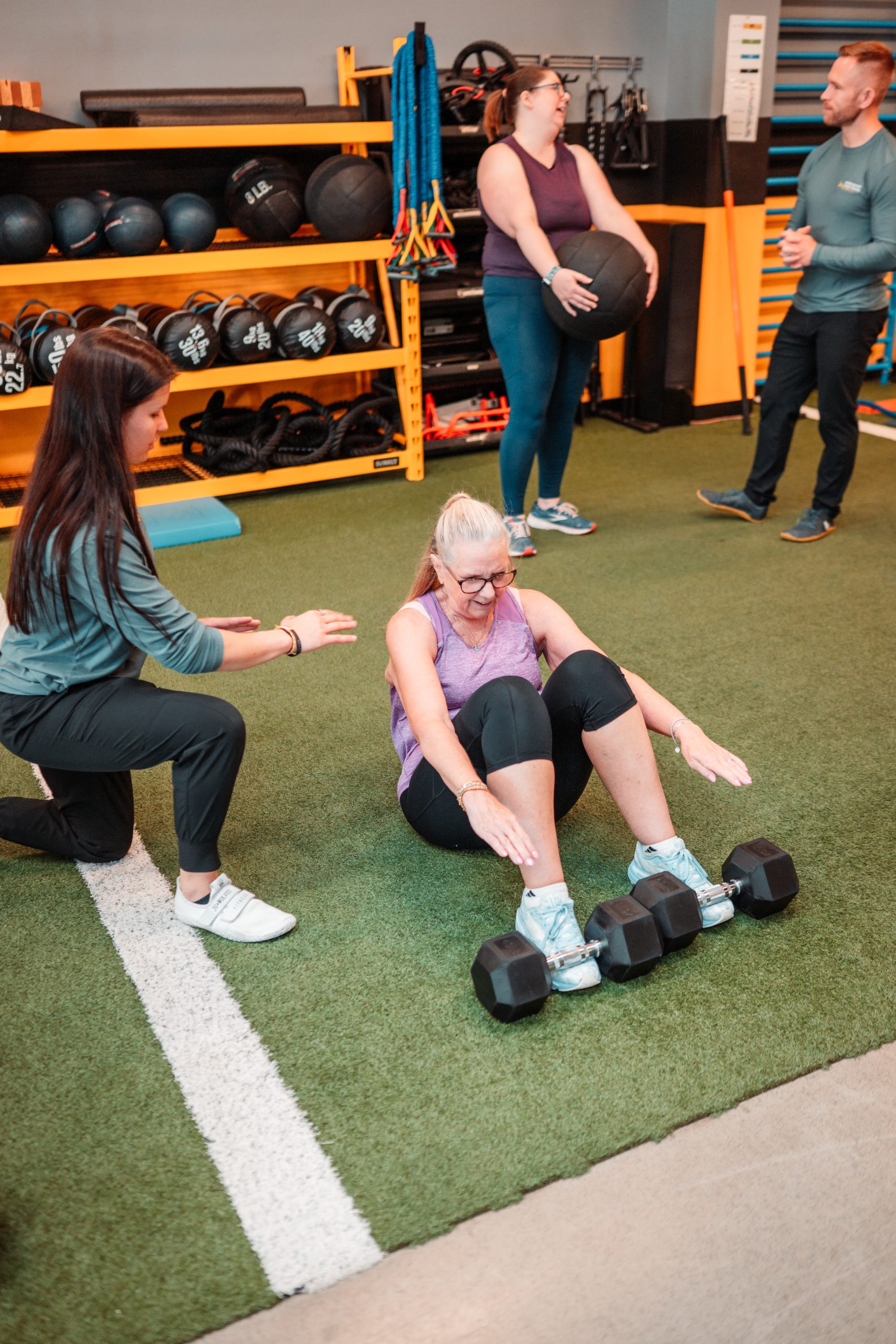 Fitness trainer assisting a client with a floor exercise during a functional fitness session at Beyond Measure Fitness Training in Naperville.