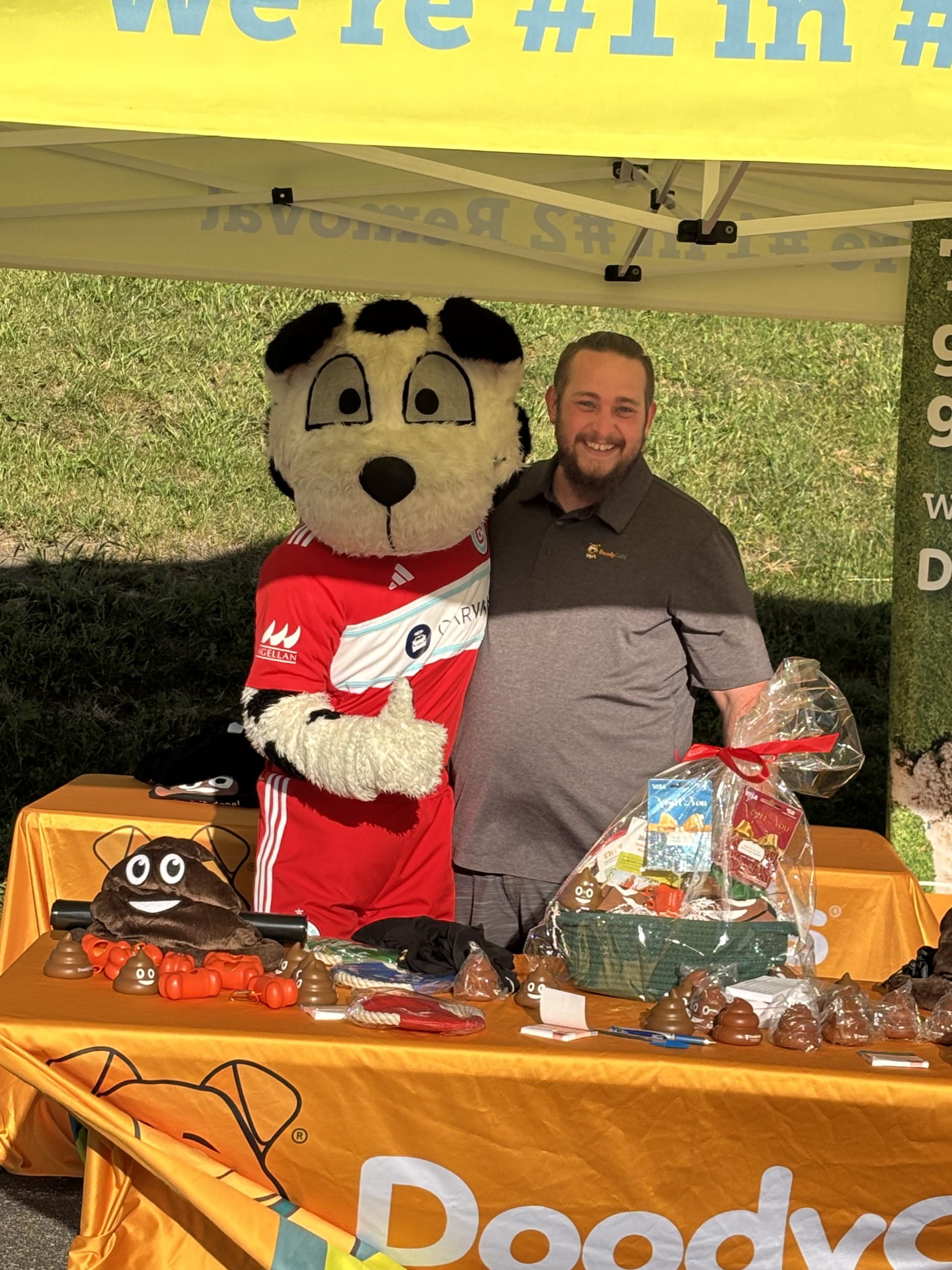 DoodyCalls Chicagoland team member and mascot at a community event in Naperville, Illinois promoting pet waste removal services.